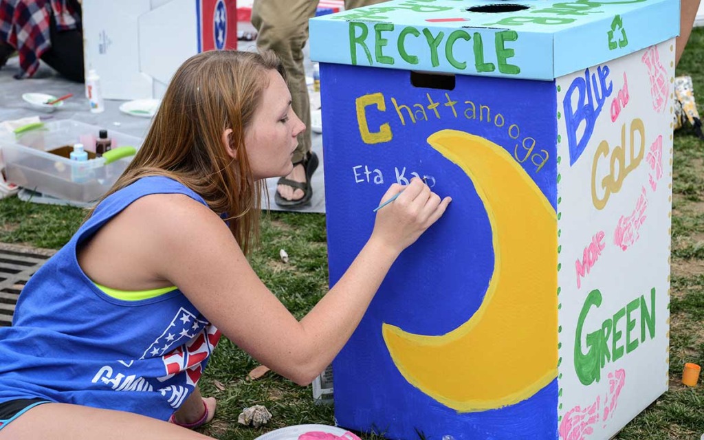 UTC student paints a recycling bin during Earth Week at UTC