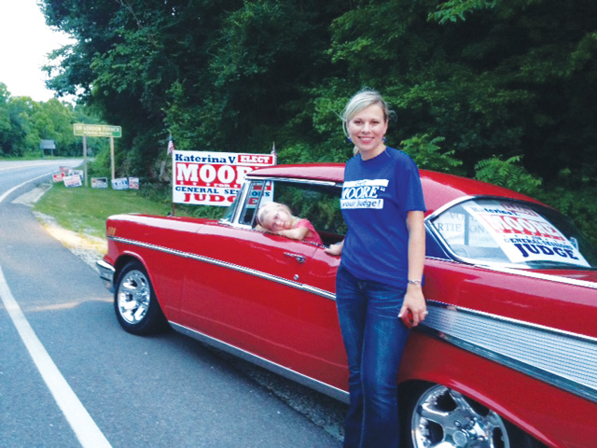 Katerina Moore and daughter campaigning on a rural road in a classic car