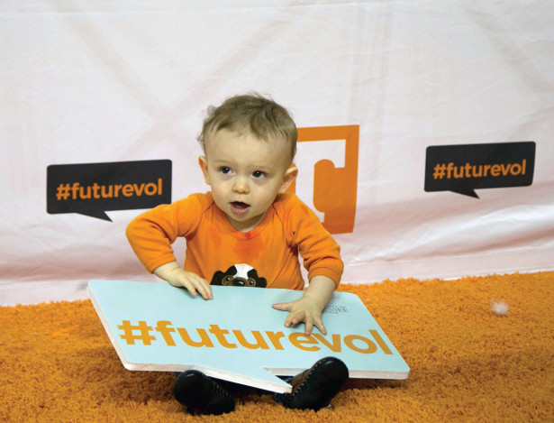 A little boy holding a 'future vol' sign