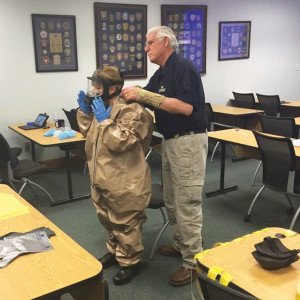 Ray Burston helps a student learn to properly dress to protect against contamination.