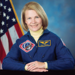 Rhea Seddon pictured in astronaut uniform in front of US flag