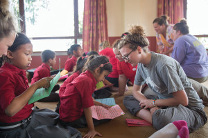 Courtney Pearson, co-founder of Letters in Motion reads together with a girl in a classroom in Nepal
