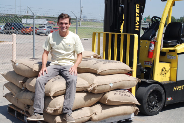 Blake Thomas seated on pallet of coffee beans in burlap sacks