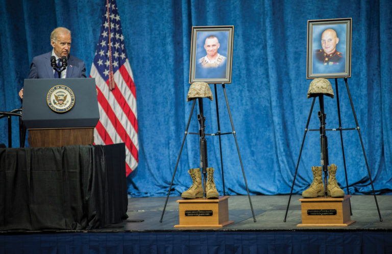 Vice President Biden at podium, with memorials to fallen military personnel to his left on a stage