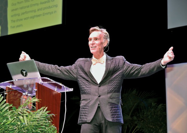 Bill Nye “the Science Guy” stands in front of a podium and his speaker notes on a laptop at Thompson Boling Arena