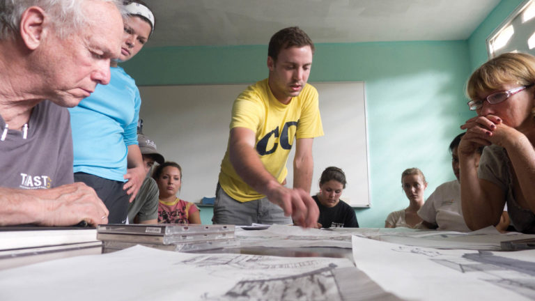 Since the 2010 earthquake, College of Architecture and Design Professor John McRae (left) has led more than 70 faculty and students in designing structures to improve life in Haiti. Here, he and students describe the students’ design for the Haitian client.