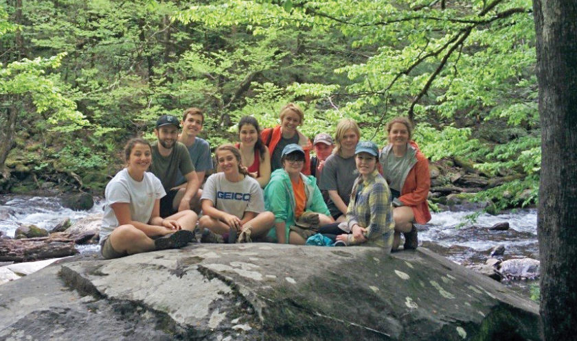 A group of students take a break on a rock by the river in Great Smoky Mountains National Park