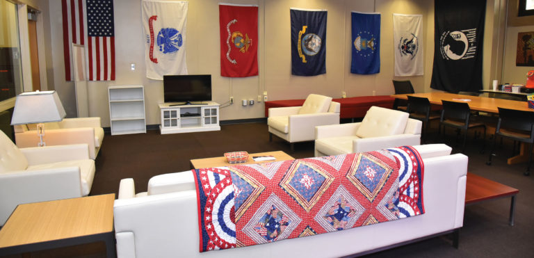 veterans resource center lounge, with flags of each military branch and quilts of valor on furniture