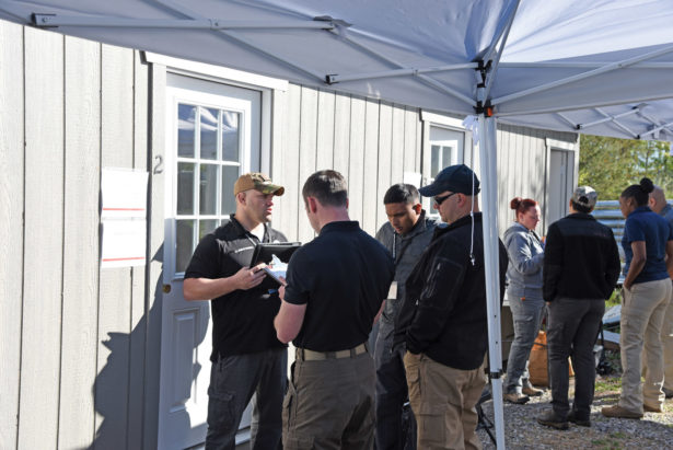 forensic specialists gather under an outdoor tent