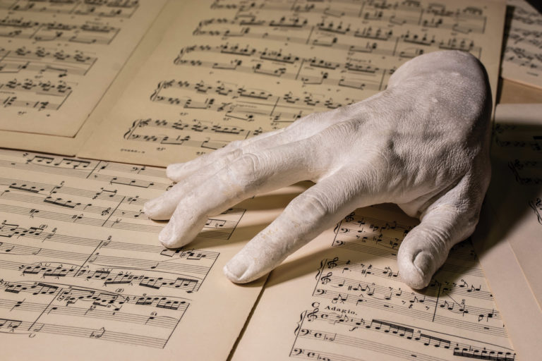 Plaster cast of a right hand photographed on sheets of music