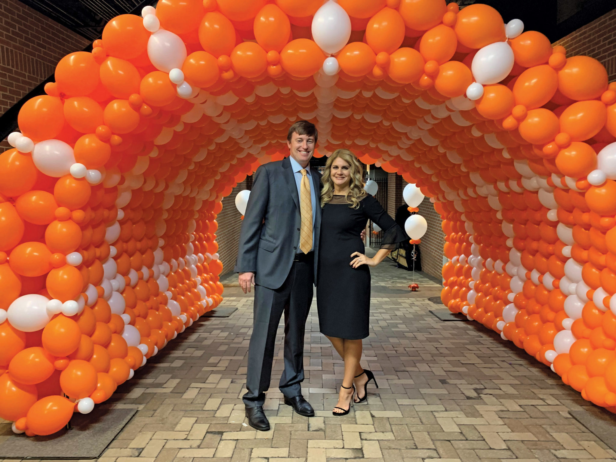 Ross and Sara Croley stand under an orange and white balloon arch at Neyland Stadium