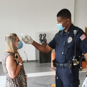 A police officer checks a staff member's temperature